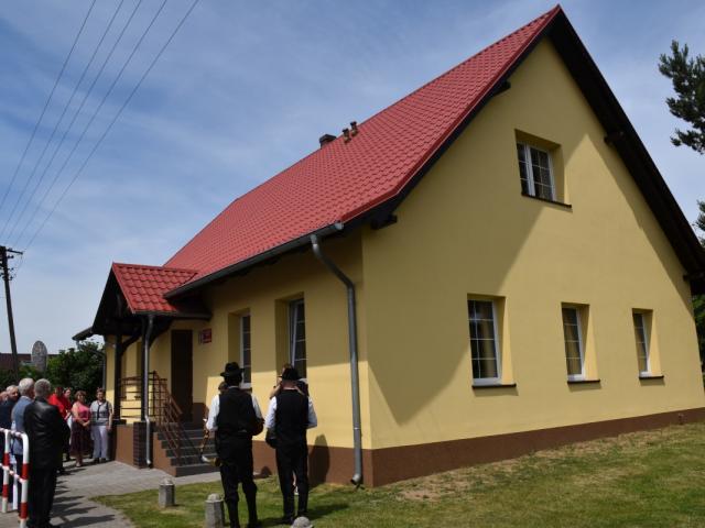 Gminne Centrum Folkloru w Bukówcu Górnym w całej okazałości, przy nim stoją uczestnicy wydarzenia