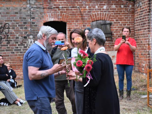 Uczestniczki spotkania wręczają kwiat Marianowi Murkowi