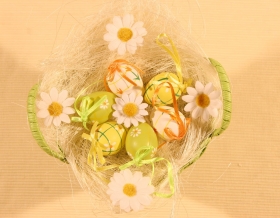 Grafika przedstawiająca koszyk wypełniony siankiem z kolorowymi jajkami i kwiatkami