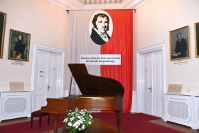 Fortepian w Sali Trójkątnej Pałacu Sułkowskich we Włoszakowicach, w tle biało-czerwona flaga z podobizną Karola Kurpińskiego i nazwą konkursu